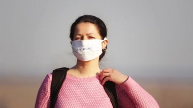 Doğadaki virüslerden maske takmış bir kızın portresi. Tıbbi maskeli bir kadın parkta yürüyor.. 