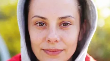 Genç ve güzel bir kız kameraya gülüyor ve lensi eliyle kapatıyor. Doğada bir kadın portresi, kamera önünde poz veriyor.. 