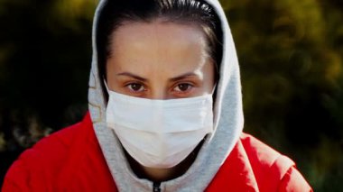 Doğadaki virüslerden maske takmış bir kızın portresi. Tıbbi maskeli bir kadın parkta yürüyor.. 