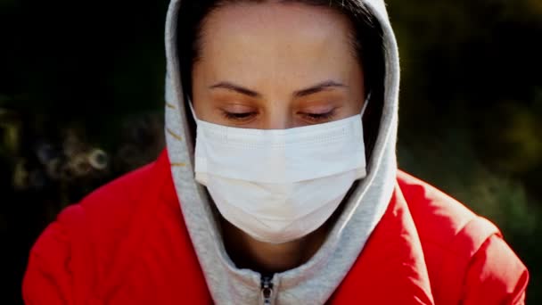 自然界のウイルスからマスクの少女の肖像画 医療マスクの女性が公園を歩いている — ストック動画