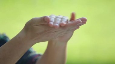 Kadın dışarıda sabunla ellerini yıkıyor. Yıkanırken yakın plan bir kızın elleri. 