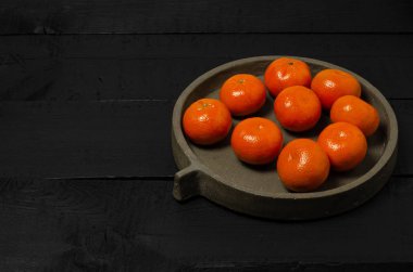 Çince portakallar siyah arkaplanda beton tabaklarda