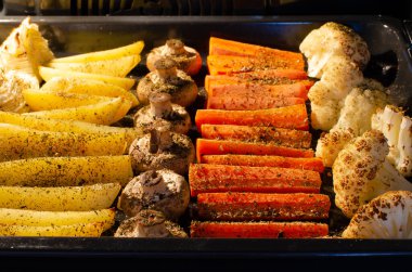 Pişirilmiş sebze tepsisi. Patates, tarla mantarı, havuç, karnabahar..