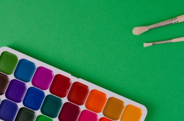 Yeşil arkaplanda fotokopi alanı ile suluboya boya ve fırçalar