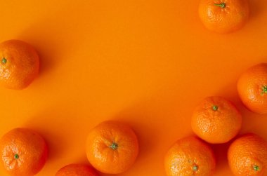 Turuncu arka planda organik mandalinalar ve fotokopi alanı. Üst görünüm