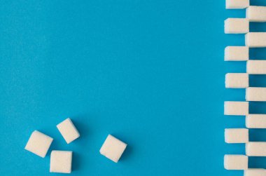 Şekeri dikey çizgi halinde mavi arkaplan üzerinde sendeleyerek kopyalama alanı ile birlikte. Üst Manzara. Satranç tahtası deseni