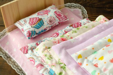 Ahşap arka plandaki bebekler için renkli küçük yatak örtüleri. Oyuncak battaniyeler. Oyuncak yastık