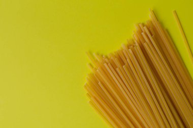 Sarı arka planda beton tabaktaki erişteler ve fotokopi alanı. Makarna. Üst görünüm.