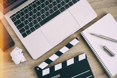 Film clapper laptop ve smartphone, ahşap sekmesinde kalem not defteri