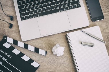 Film clapper laptop ve smartphone, ahşap sekmesinde kalem not defteri