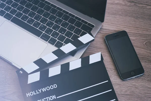 Película clapper portátil y teléfono inteligente en la mesa de madera —  Fotos de Stock