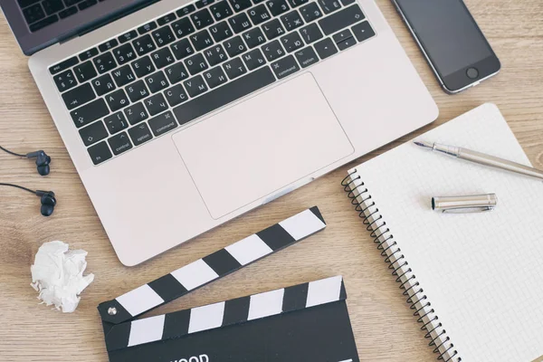 Film kläpp laptop och smartphone, penna anteckningar på fliken trä — Stockfoto