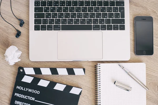 Laptop und Smartphone für Filmklöppel, Notizblock auf der Holzlasche — Stockfoto