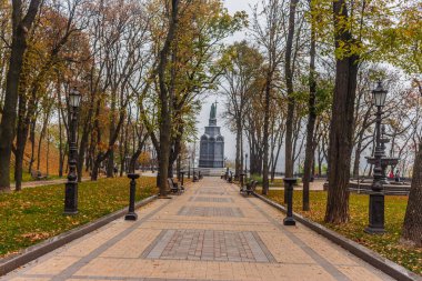Kiev, Ukrayna - 27 Ekim 2019: Kiev parkında sonbahar. Vladimir Anıtı, Vladimir parkındaki sarı ağaç yaprakları ve kentsel Volodymyrska Tepesi 'ndeki Dinyeper Nehri manzarası boyunca uzanır.