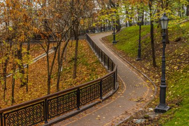 Kiev, Ukrayna - 27 Ekim 2019: Kiev parkında sonbahar. Vladimir Anıtı, Vladimir parkındaki sarı ağaç yaprakları ve kentsel Volodymyrska Tepesi 'ndeki Dinyeper Nehri manzarası boyunca uzanır.
