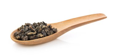 Tahta kaşıkta kuru çay yaprakları beyaz arka planda izole edilmiş.