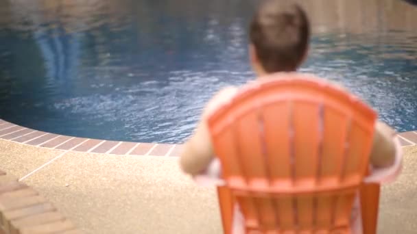 Uomo Siede Una Sedia Bordo Piscina — Video Stock