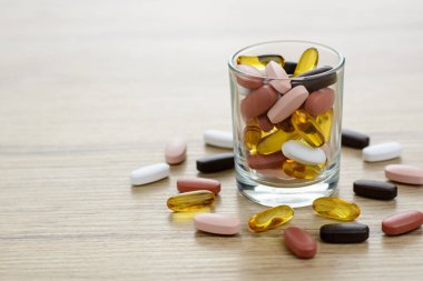 Küçük bardakta Fishoil kapsülleri ve Multivitamin takviyeleri
