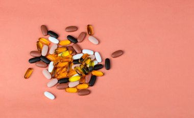 Pembe arka planda Fishoil kapsülleri ve Multivitamin takviyeleri
