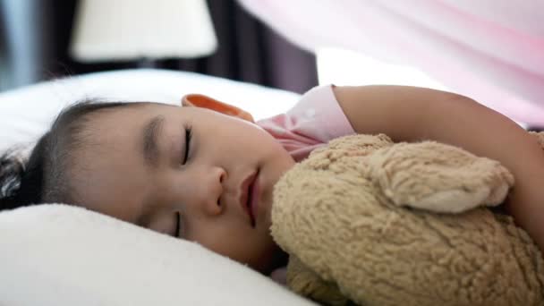 かわいいアジアの赤ちゃんの女の子を閉じますベッドの上で寝て 母は赤ちゃんに毛布を入れます — ストック動画