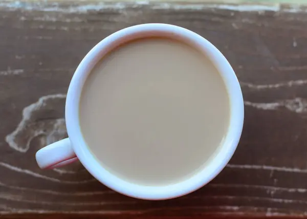Φλιτζάνι καφέ με γάλα σε ξύλινο τραπέζι — Φωτογραφία Αρχείου