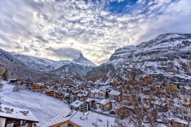 Önünde bulutlar ve İsviçre köyü olan Matterhorn Dağı manzarası