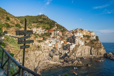İtalya 'nın Cinq Terre kentinde yaz mevsiminde ön planda yol işareti olan Manarola köyü.