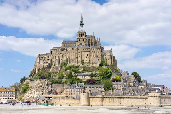 Mont Saint Michel 'in uzak manzarası alçak gelgitte Fransa' nın batısında mavi gökyüzünde bulutlarla