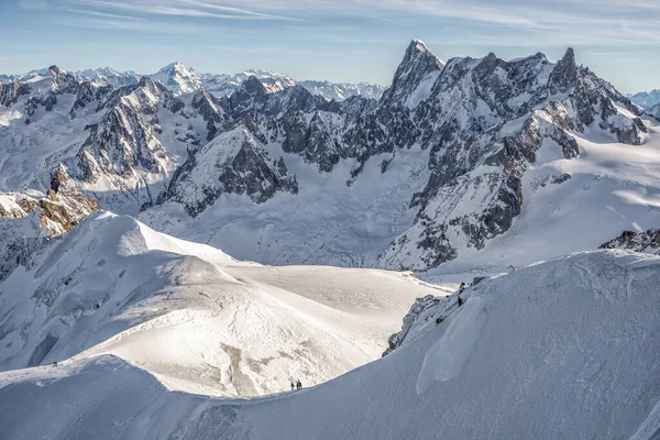 Caminante esquiador lento caminar hacia abajo en una ladera de montaña de nieve masiva en la cima de los Alpes mont blanc —  Fotos de Stock