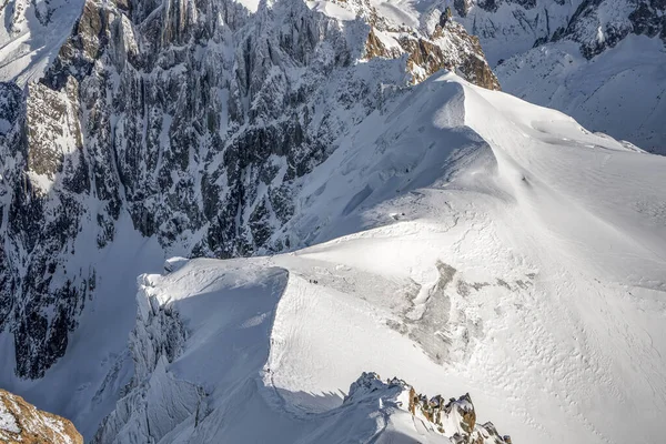 Caminante esquiador lento caminar hacia abajo en una ladera de montaña de nieve masiva en la cima de los Alpes mont blanc —  Fotos de Stock