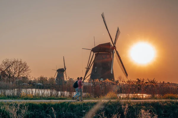 Turisti che passano dal mulino a vento a Kinderdijk durante il tramonto vicino Rotterdam — Foto Stock