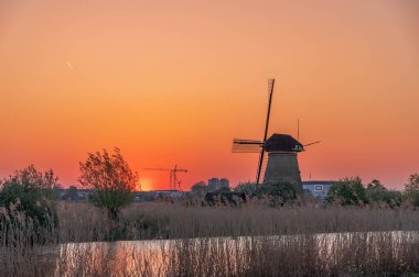 Hollanda, Rotterdam yakınlarındaki Kinderdijk 'teki değirmenlerde altın kırmızısı günbatımı