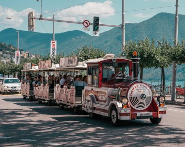 Lugano, İsviçre - 4 Ağustos 2019: Lugano Gölü kıyısındaki klasik turistik trende turistler