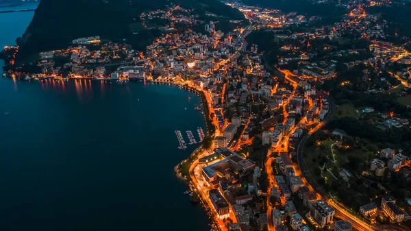 Высокоугловой беспилотник ночью, снимок городских уличных фонарей у озера в Лугано, Швейцария — стоковое фото