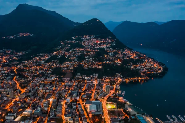 High angle aerial drone night shot of city street lights by lake monte bre in Lugano, Switzerland — Stock Photo, Image