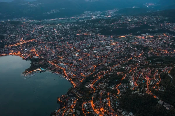 Wysoka kąt lotu drona widok z lotu ptaka Lugano nad jeziorem z miejskich świateł ulicznych po zachodzie słońca w Szwajcarii — Zdjęcie stockowe