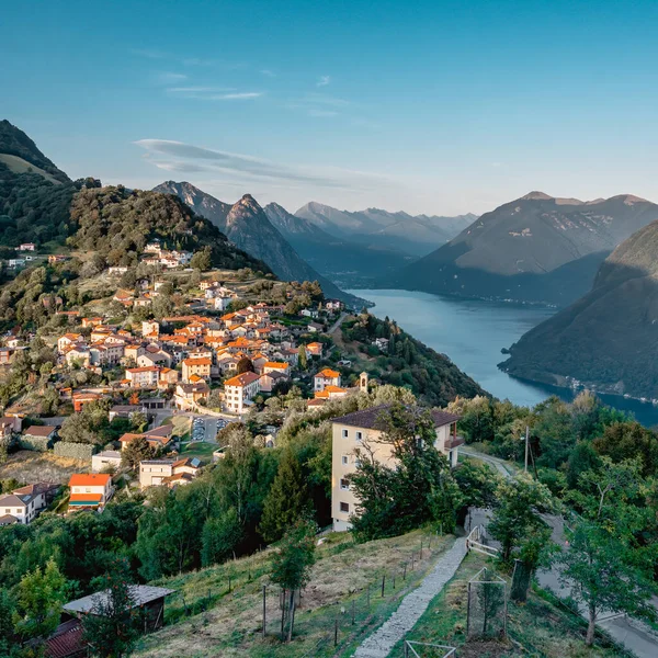 Uitzicht op het Zwitserse dorp bre sopra en het meer van Lugano voor zonsondergang vanaf Monte Bre in Lugano — Stockfoto