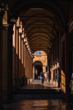 Bologna, İtalya - 8 Ağustos 2019: Peple sabah güneş ışığında Roma tarzı sütunlarla portico geçidinde yürüyor