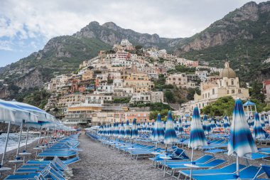 Arka planda Amalfi kayalıkları olan şemsiye yataklı Positano plajı