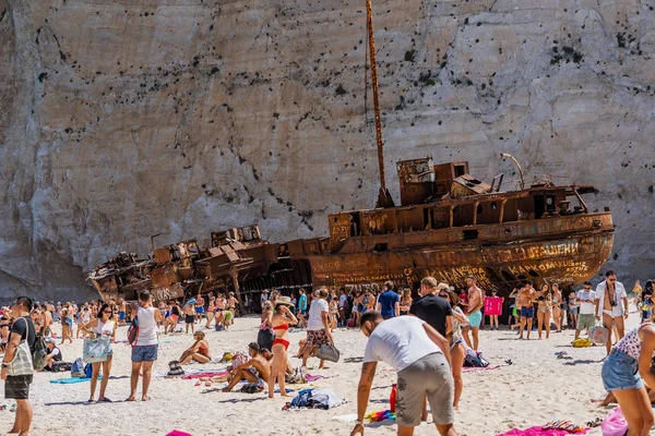 希腊Zakynthos - 2019年8月20日：游客们在沉船湾的肚脐海滩的锈迹斑斑的弃船前享受夏天的中午 — 图库照片