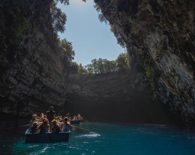 Kefalonia, Yunanistan - 22 Ağustos 2019: Turistler Melissani göl mağarasında teknede fotoğraf çekiyorlar