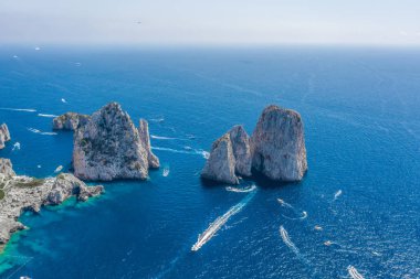 Capri Adası açıklarındaki Tyrhenian Denizi 'nde yaz mevsiminde Faraglioni kireçtaşı kayalıklarının hava aracı görüntüsü.