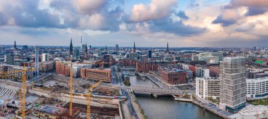 Günbatımından önce Hamburg limanının panoramik hava aracı görüntüsü. Tarihi şehir merkezinde şiddetli fırtınalı bulutlar var.