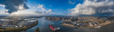 Hava aracı, güneş batmadan önce Hamburg limanının panoramik görüntüsünü deniz limanında dramatik fırtınalı bulutlar ile izliyordu.
