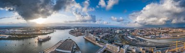 Hava aracı, güneş batmadan önce Hamburg limanının panoramik görüntüsünü deniz limanında dramatik fırtınalı bulutlar ile izliyordu.