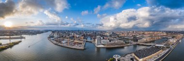 Günbatımından önce Hamburg limanının panoramik hava aracı görüntüsü. Tarihi şehir merkezinde şiddetli fırtınalı bulutlar var.