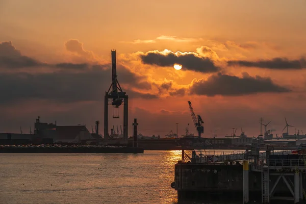 重いクレーンでハンブルクの港で劇的な雲と夕日 — ストック写真
