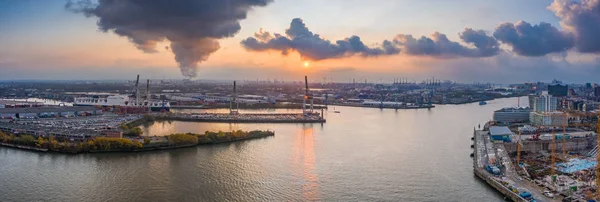 ハンブルク港の空中ドローンパノラマビュー造船所のクレーン活動上の煙や重い雲と日没時に — ストック写真