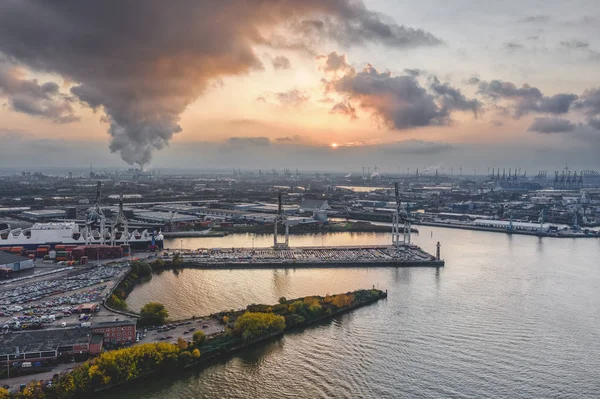 ハンブルク港の空中ドローンからの眺め海上の造船所の上の煙と重い雲と日没時 — ストック写真