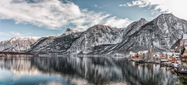Karlı köyün panoramik manzarası. Avusturya 'da kışın açık gökyüzü olan kar dağının eteklerindeki Hallstatt Gölü.
